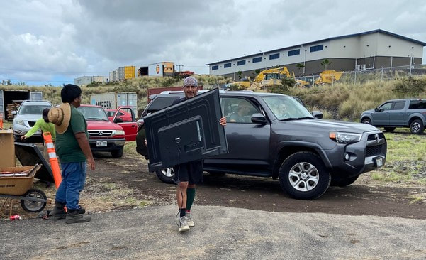 Mr. K's staff carrying a large flat screen tv from an SUV at the Kona Collection